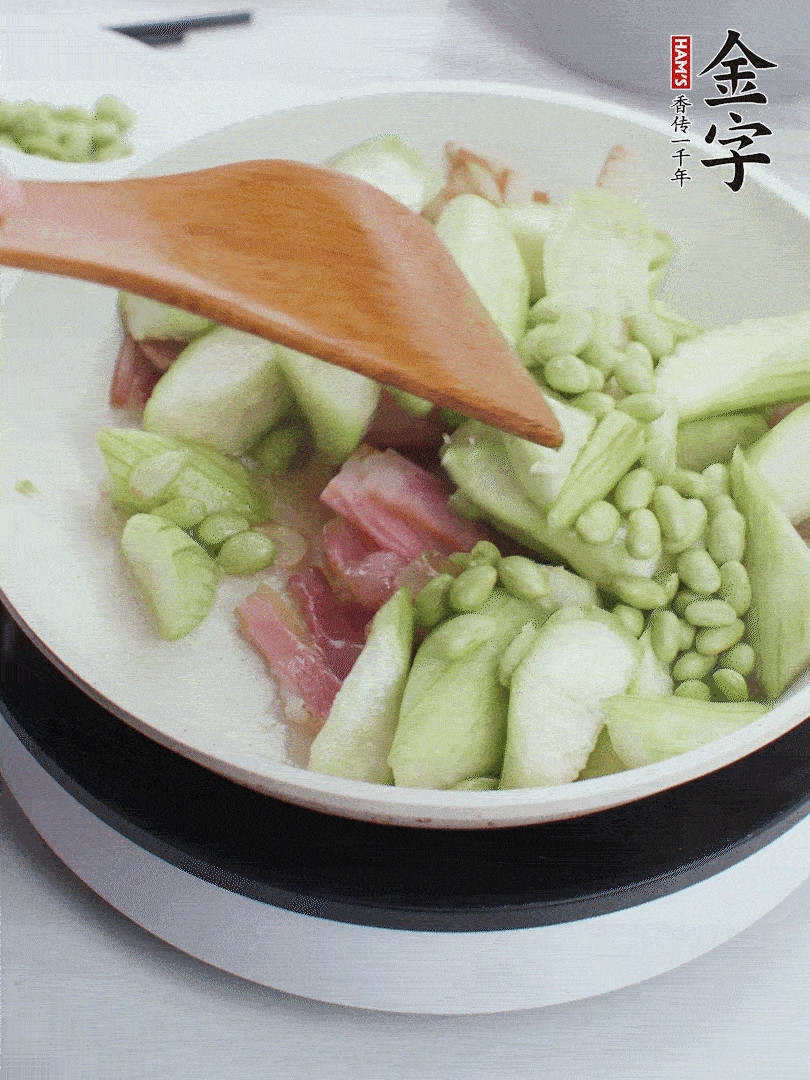 依次下絲瓜、青豆翻炒，炒至絲瓜打蔫縮小。